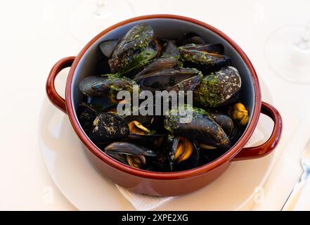 Steamed mussels with garlic butter sauce in clay pan Stock Photo