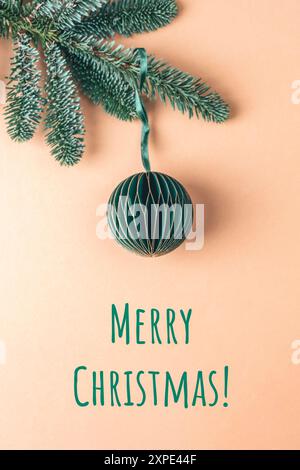 Christmas bauble on fir branch on neutral beige background. Christmas, New Year concept. Stock Photo