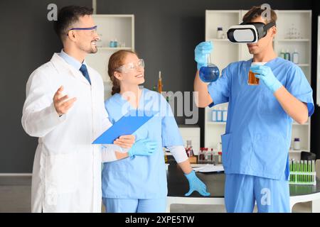 Male doctor with chemical flasks using VR glasses in laboratory Stock Photo