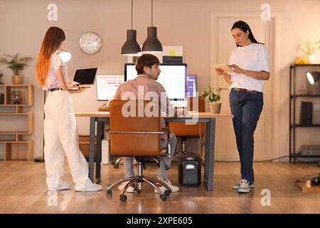 Team of programmers working in office at night, back view Stock Photo