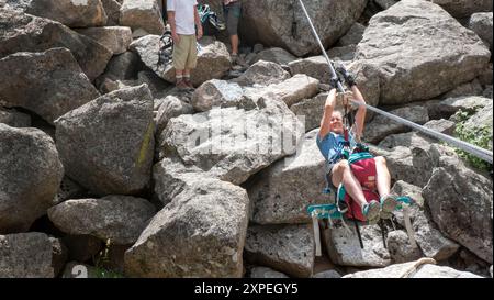 A single adult women crossing a tyrolean  traverse suspended above Boulder Creek in Boulder Canyon, Boulder , Colorado Stock Photo