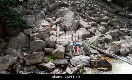 A single adult women crossing a tyrolean  traverse suspended above Boulder Creek in Boulder Canyon, Boulder , Colorado Stock Photo