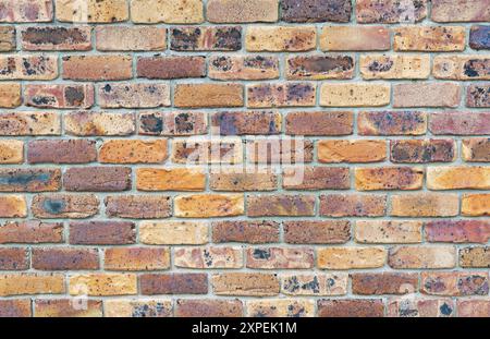 multi colored brick wall with a grungy appearance and cement joints, background texture use. Stock Photo