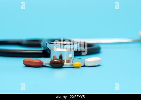 A doctor's stethoscope is on a table with a variety of pills. The pills are in different colors and shapes, and the stethoscope is placed on top of th Stock Photo