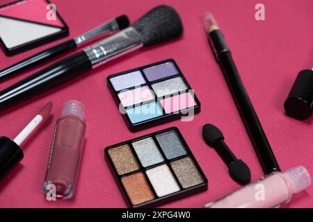 Various decorative cosmetics and brushes on a pink background. Stock Photo