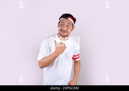 An man white t-shirt outfit and a Indonesian flag headband celebration poses for Indonesian Independence Day. Stock Photo