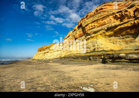 A stunning coastal landscape featuring colorful cliffs and a sandy beach under a bright blue sky at the Torrey Pines State Beach Stock Photo