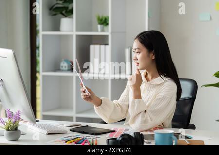 Young Female Graphic Designer Working on creativity Project in Modern Office with Digital Tools and Color Samples Stock Photo