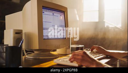 Caucasian Male Stock Trader Using Old Desktop Computer With Financial Candlestick Chart In Retro Garage. Man Analyzing Price Action Before Entering Trade, Starting Investment Fund In Nineties. Stock Photo