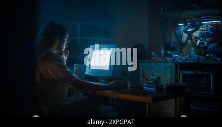 Hispanic Female Programmer Using Old Desktop Computer In Retro Garage Late At Night. Evil Hacker Searching For Software Vulnerabilities, Doing DDOS Attack, Coding Trojan Horse Programs, Stealing Data. Stock Photo