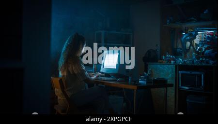 Hispanic Female Programmer Using Old Desktop Computer In Retro Garage Late At Night. White Hat Hacker Searching For Software Vulnerabilities, Coding Cyber Security System, Protecting Data In Nineties. Stock Photo