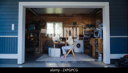 Hispanic Female Developer Programming On Old Desktop Computer In Retro Garage With Random Appliances. Young Woman Working On Innovative Online Service Startup Company In Nineties. Nostalgia Concept. Stock Photo
