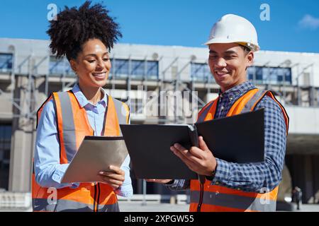Smiling Construction Workers Discussing Blueprints at a Building Site Stock Photo