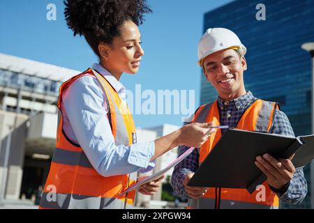 Diverse Construction Workers Collaborating on Outdoor Building Project Stock Photo