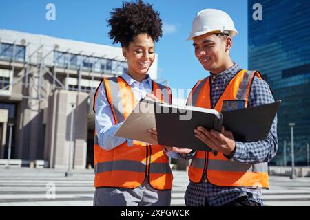 Diverse Engineers Collaborating on Construction Site with Blueprints Stock Photo
