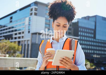 Confident Female Construction Worker Using Tablet on Worksite with Coffee Stock Photo