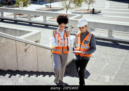 Diverse Construction Workers Collaborating with Digital Devices on Outdoor Site Stock Photo