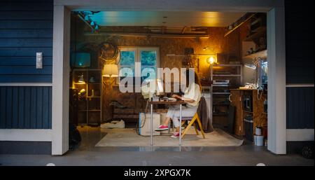 Hispanic Female Software Developer Programming On Old Desktop Computer In Retro Garage In the Evening. Woman Working On Innovative Online Service Startup Company In Nineties. Nostalgia Concept. Stock Photo