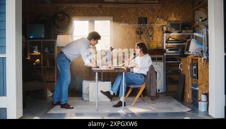 Two Caucasian Male Stock Brokers Working In Retro Garage, Using Old Desktop Computer With Candlestick Chart And Landline Phone To Pitch A Public Company To Investor. Partners Trading On Stock Exchange Stock Photo