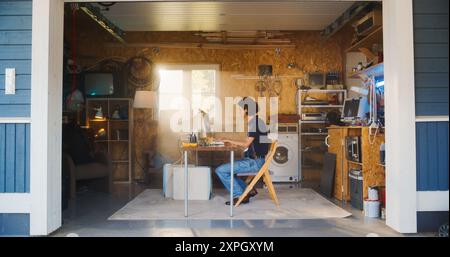 Caucasian Male Software Engineer Programming On Old Desktop Computer In Retro Garage With Random Appliances. Man Working On Innovative Fintech Startup Company In Nineties. Nostalgia Concept. Stock Photo