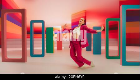 Professional Female Performer Energetically Rehearsing a Modern Dance Choreography in a Colorful Spacious Studio. Stylish Woman Looking at the Camera and Dancing Expressively, Practicing Her Routine Stock Photo