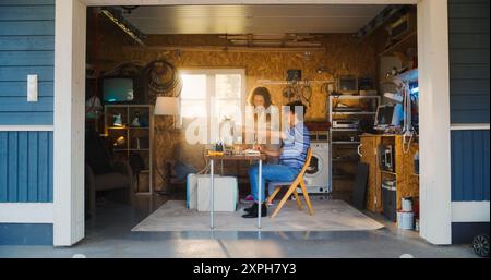 Caucasian Male Software Developer And Hispanic Female Designer Talking And Using Old Desktop Computer in Retro Garage. Diverse Startup Founders Working On Online Service In Nineties. Nostalgia Concept Stock Photo