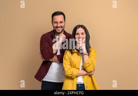 Charming young man and woman with hands on chins smiling and looking at camera. Confident joyful boyfriend and girlfriend wearing casuals and posing o Stock Photo