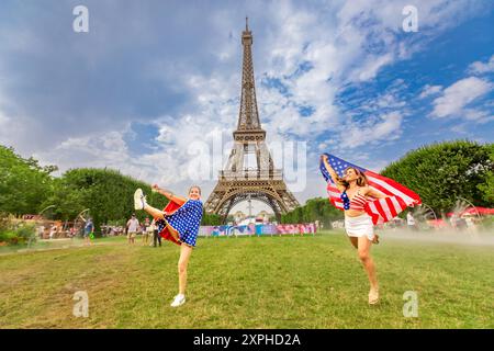 Patriotic American Woman jumping and cheering for Team USA and the Paris 2024 Olympics in front of the Eiffel Tower, Paris, France, Europe Copyright: Stock Photo