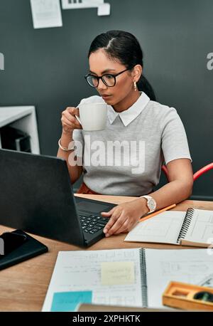 Woman, architect and reading on laptop with coffee in morning with thinking, decision or design. Person, tea cup and computer for review with Stock Photo