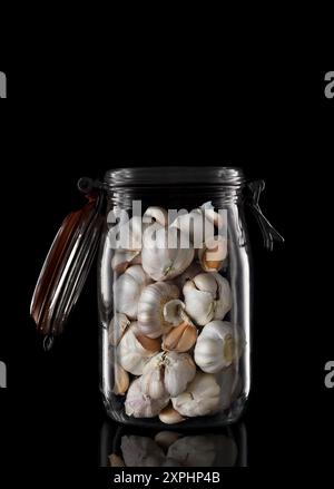Garlic Cloves in a glass storage or canning jar isolated on black with reflection, with lid open. Stock Photo