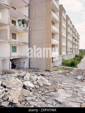 An abandoned Plattenbau building in Eisenhüttenstadt undergoing demolition. The image shows visible debris and an exposed interior, including a room with tropical wallpaper, reflecting the decay of living spaces and former dreams. Stock Photo