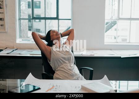 Blueprint, relax and woman at desk for architecture, project management and creative development. Business, building plan and professional designer in Stock Photo