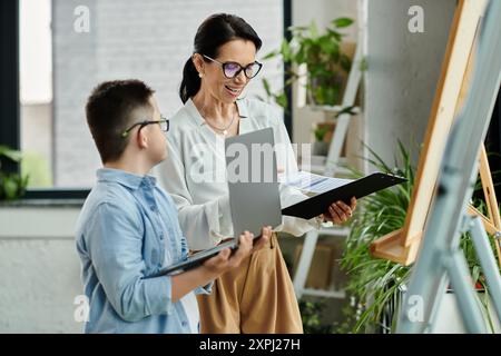 A mother works on her laptop while her son, who has Down syndrome, works on his own laptop. Stock Photo