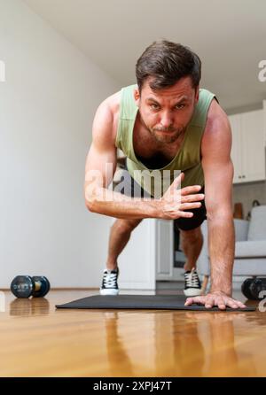 man doing plank shoulder tap exercise at home. Healthy and sporty lifestyle. Stock Photo