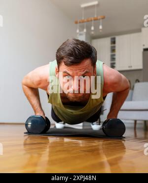 man doing push-ups with dumbbells at home Stock Photo
