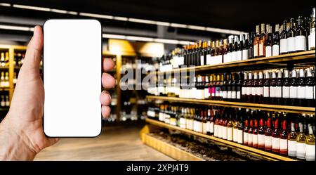Mobile phone with blank screen in hand on background of blurred liquor store. Stock Photo