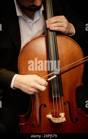 Vertical cropped shot of unrecognizable male classical music artist playing cello with bow Stock Photo