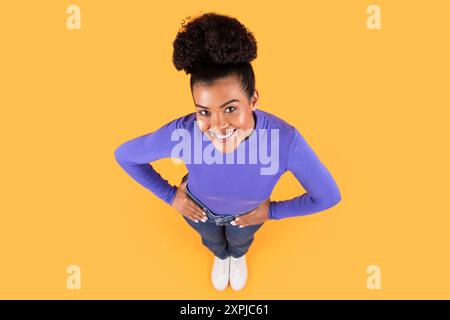 Young Woman Smiling Joyfully While Posing On Yellow Stock Photo