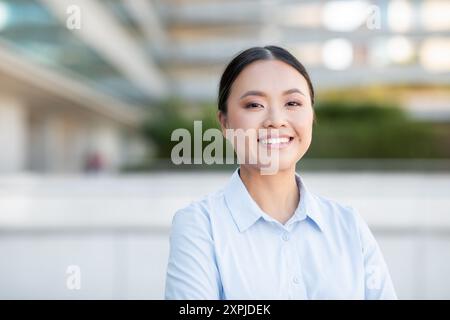 Smiling Young Woman in Light Blue Blouse at Outdoor Stock Photo