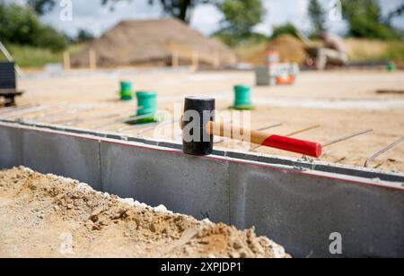 Close up of a rubber hammer standing on concrete curb stones, blurry background wit construction site workers  Stock Photo