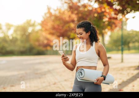 Young Woman Enjoying Outdoor Exercise While Checking Phone Stock Photo