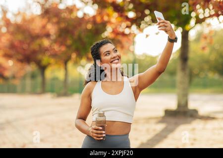 Young Woman Enjoys Autumn Day by Taking Selfie in Park Stock Photo