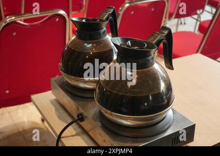 Two transparent glass kettles containing black coffee are on an electric heating stove. Stock Photo