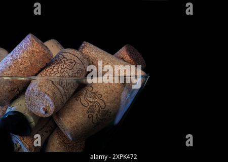 Macro photo of random wine bottle corks in a martini glass. Black background with space for copy. Stock Photo