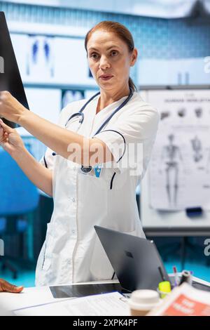 Doctor showing the x ray scan results to her colleagues in a meeting, people with expertise collaborating on treatment options based on diagnostic. Disease prevention strategies with radiography. Stock Photo