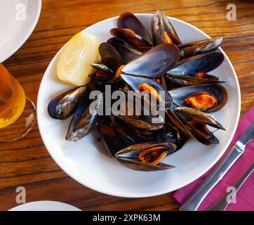 Steamed mussels with lemon wedge on white plate Stock Photo