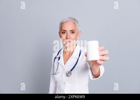 Photo of aged lady professional doctor hold pills bottle wear white coat isolated on grey color background Stock Photo
