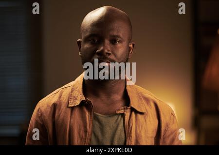 Young bald serious African American man with beard looking at camera while standing in home environment during argument Stock Photo