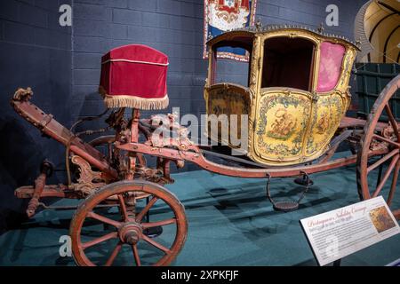 LURAY, Virginia, United States — A Portuguese Nobility Carriage, specifically a Berlin Coupe de Gala from the mid-18th century, is displayed at the Car and Carriage Caravan Museum in Luray, Virginia. The carriage features a coupe design, which is cut in front to allow for only two seats. This ornate vehicle represents a fine example of 18th-century European aristocratic transportation. Stock Photo