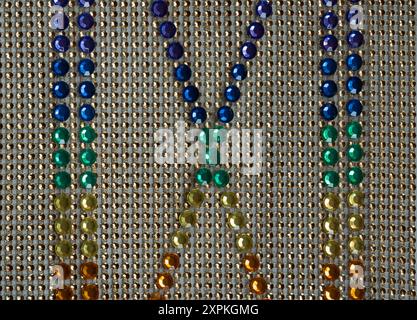 Roman numerals, numbers, cross or X designs are made from faux rhinestones on a gold grid of gems. Colorful rows of jewels make a flat display, Stock Photo